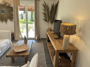 Una sala de estar con sofá, mesa de centro, mesita auxiliar de madera y una lámpara.