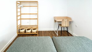 Ein kleiner, gut beleuchteter Raum mit Schreibtisch, Stuhl und eingebautem Kleiderschrank mit Regalen und Ablagefläche.