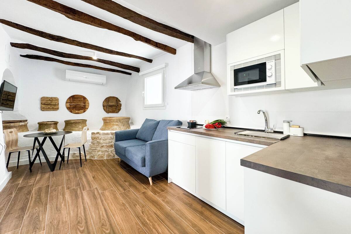 A modern kitchen with white cabinetry, a built-in microwave, and a wooden dining table with chairs.