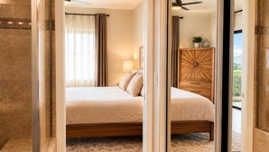 Ein Schlafzimmer mit Bett, Nachttisch, Kommode und Blick ins Freie.