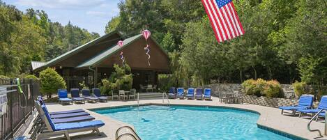 A swimming pool with lounge chairs and a flag.