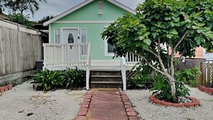 A small, single-story house with a green exterior and a white porch. - Sugar Shack Bungalow by Ryson Vacation Rentals (Galveston)