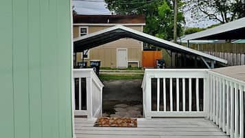 Um deck de madeira com corrimãos brancos que dá para uma porta de garagem.