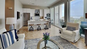 Un salon moderne avec un canapé, une table basse et une vue sur la cuisine et le balcon.