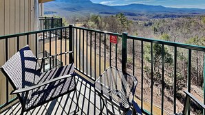 A balcony with outdoor seating and a view of mountains.