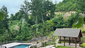 A pool surrounded by a black metal fence, a wooden gazebo, and a well-maintained lawn.