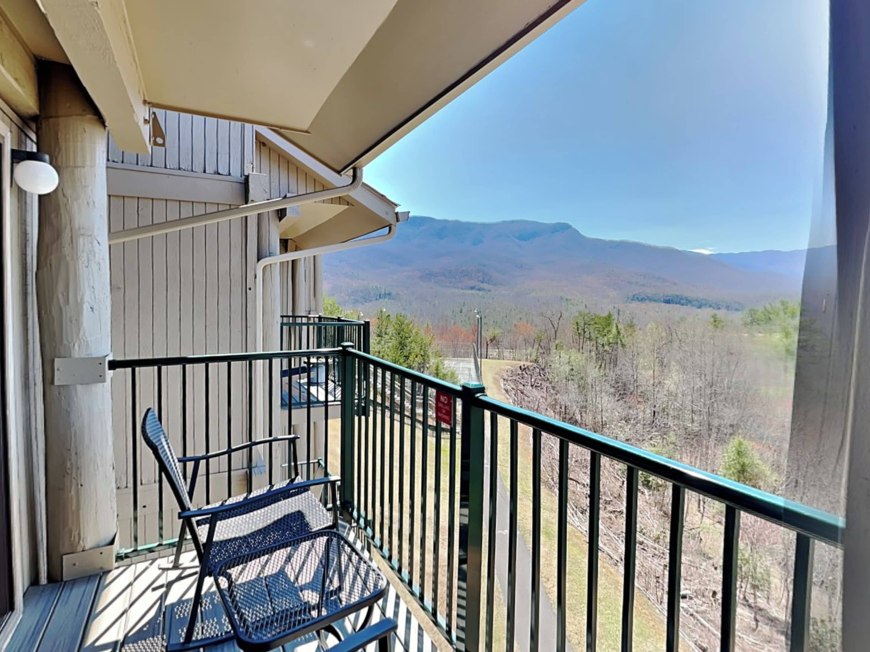 Un balcon avec vue sur les montagnes, une chaise et une rambarde.