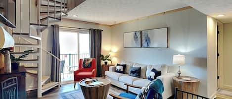 A spacious living area with a staircase, a sofa set, a coffee table, and a dining table.