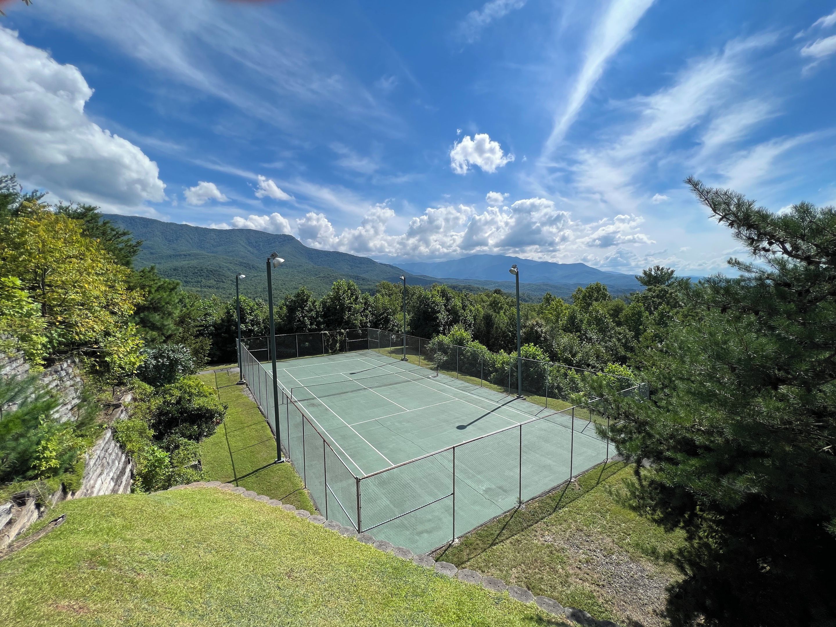 A tennis court surrounded by trees and mountains.