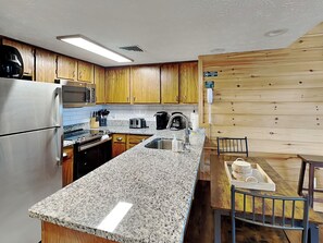A kitchen with wooden cabinets, a stainless steel refrigerator, a microwave, a toaster, and a sink.
