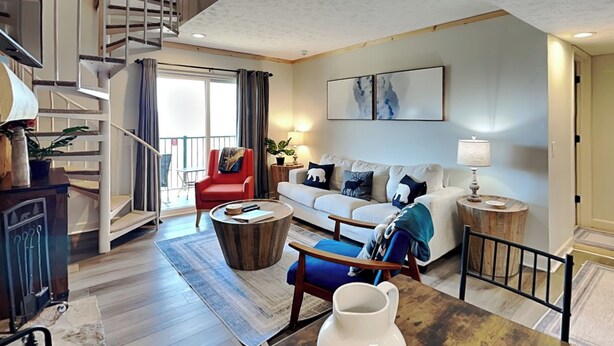 A spacious living area with a staircase, a sofa set, a coffee table, and a dining table.