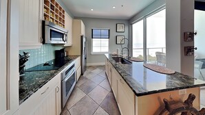 Una cocina moderna con una isla grande, electrodomésticos integrados y vistas al exterior.