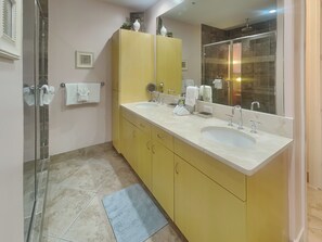 A bathroom with two sinks, a large mirror, and a shower. - Western Waves by Ryson Vacation Rentals (Galveston)