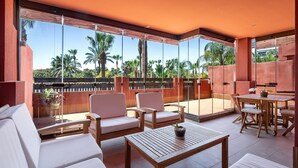 A spacious balcony with a view of palm trees, furnished with white sofas, a wooden table, and a dining set. - Ref. 565600 (Motril)