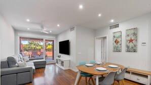 A modern living room with a grey sofa, a wooden dining table set for four, and a flat-screen TV mounted on the wall. - Ref. 565600 (Motril)