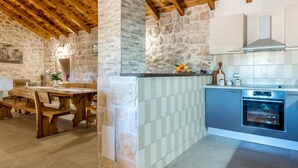 Une cuisine rustique avec des murs en pierre, des poutres en bois et un four moderne.