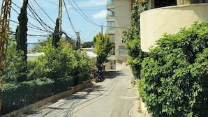 Edificio residencial con balcón curvo, rodeado de vegetación y líneas eléctricas.