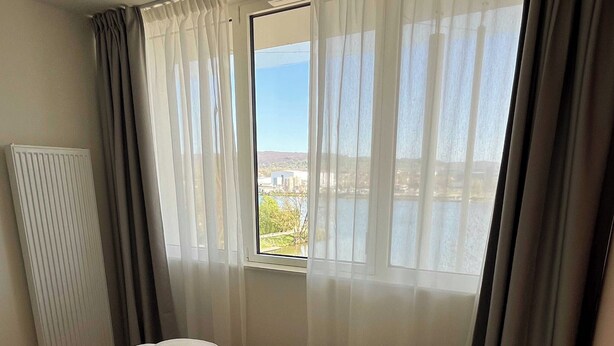 Une chambre à coucher avec un lit, une fenêtre avec des rideaux et un radiateur.