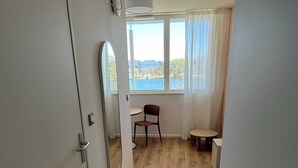 Une pièce avec un plancher en bois, une chaise, une petite table, une fenêtre donnant sur un paysage et une porte.