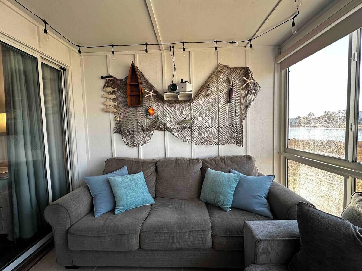A cozy living room with a grey sofa, blue cushions, and a decorative wall hanging.