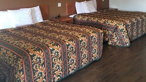 Une chambre d’hôtel avec trois lits, chacun recouvert d’une couvre-lit à motifs et agrémenté d’oreillers blancs. La chambre est dotée d’un plancher en bois et d’un mur d’accent de couleur marron.