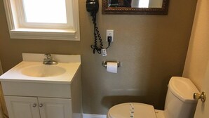 Une salle de bain avec un lavabo blanc, des toilettes et un miroir au-dessus du lavabo.