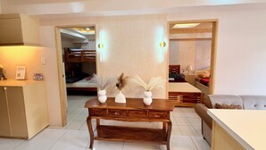 Una habitación de hotel con un escritorio de madera, un sofá, una litera y una lámpara moderna.