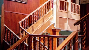 A wooden staircase with a handrail, a sign indicating room number 606, and a view of the interior space. - KINTU PLAZA HOSPEDAJE (Cuenca)