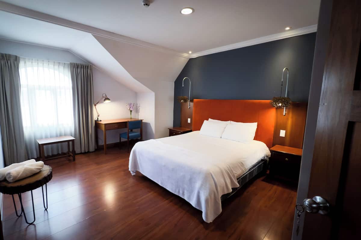 Habitación de hotel con cama, escritorio, silla y vistas al exterior.