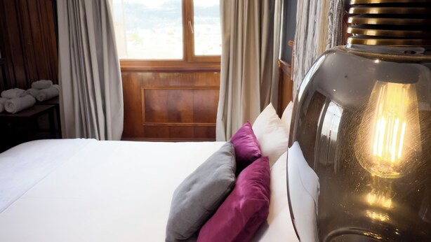 A hotel room with a large bed, a view through a window, and a unique lamp. - KINTU PLAZA HOSPEDAJE (Cuenca)