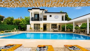 A modern two-story building with a pool, outdoor seating, and a covered patio area. - Bova Rooms (Kemer)