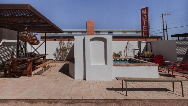 A motel with a patio area featuring outdoor seating, a pool, and a clear blue sky. - Motel Marfa (Marfa)