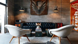 A modern living room with a black leather sofa, two white armchairs, a coffee table, and a decorative bird mural on the wall. - Motel Marfa (Marfa)