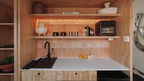 A compact kitchen with wooden cabinetry, a built-in sink, a coffee maker, and a small countertop with lemons and a mug. - Motel Marfa (Marfa)