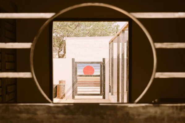 A view through a circular window with a wooden door and a red circle on the door.