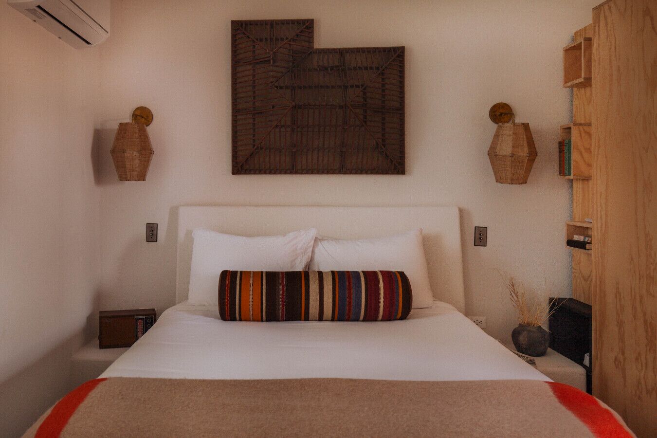 Une chambre à coucher comprenant un lit, une œuvre d’art accrochée au mur, deux tables de chevet et une armoire en bois.