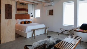 A bedroom with a bed, bench, and seating area. - Motel Marfa (Marfa)