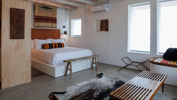 A bedroom with a bed, bench, and seating area. - Motel Marfa (Marfa)