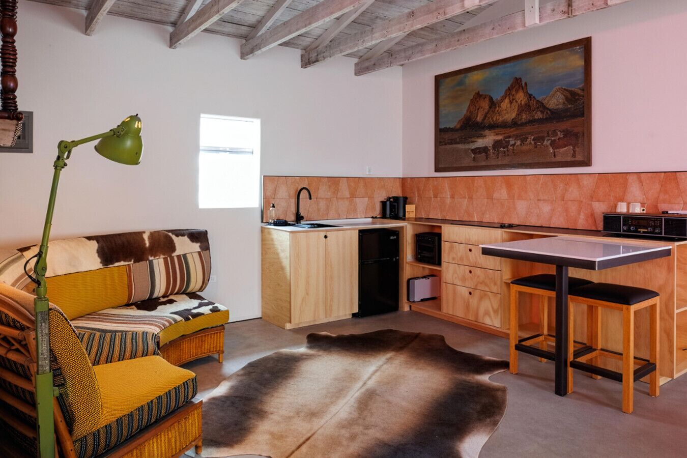 Un salon confortable avec un canapé, une table à manger, un coin cuisine et un tableau accroché au mur.