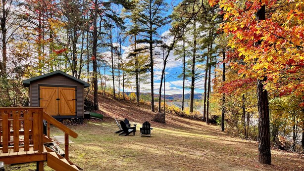 Eine Hütte mit einer Holzterrasse und zwei Adirondack-Stühlen.
