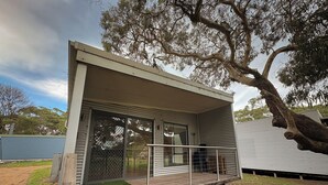 A modern, single-story building with a flat roof, large windows, and a covered porch area.