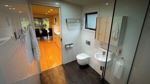 A modern bathroom with a toilet, sink, and glass shower enclosure.