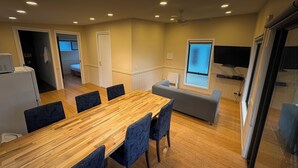 A modern kitchen with a wooden dining table and chairs, a built-in oven, and a window with a view.