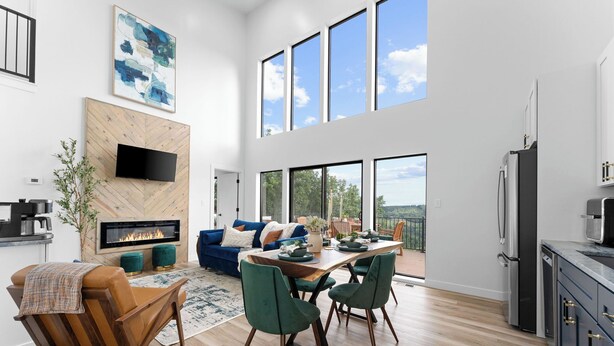 A modern kitchen with a large island, a dining area with green chairs, and a fireplace. - Lux Lakeview Table Rock Branson w/ Pool & Hot Tub (Omaha)
