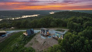 A modern house with a pool, surrounded by lush greenery and a scenic view of a lake and mountains. - Lux Lakeview Table Rock Branson w/ Pool & Hot Tub (Omaha)