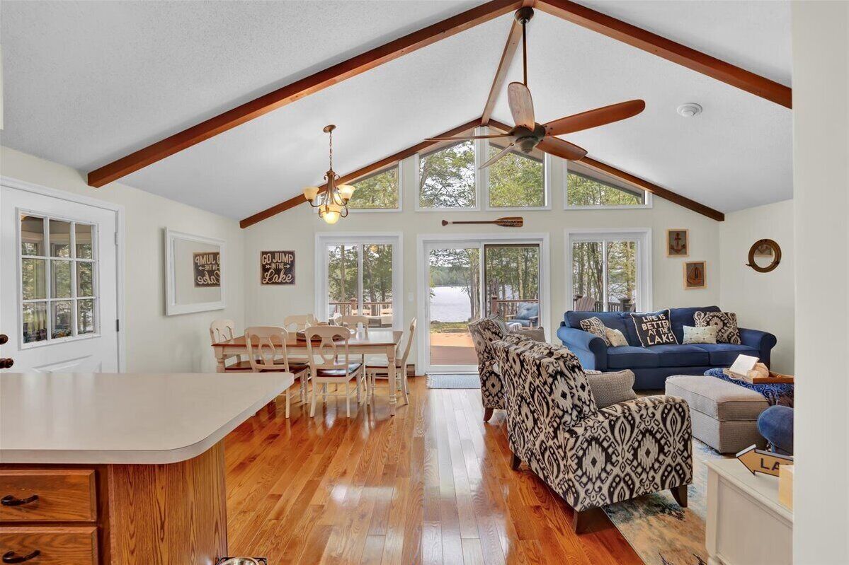 A spacious living area with a high ceiling, wooden beams, a dining area, and a view of the outdoors.