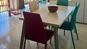 Een eethoek met een tafel, stoelen en een schaal. Er is een trap en een uitzicht op het buitengebeuren.