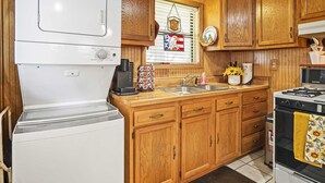 A compact kitchen with wooden cabinets, a white refrigerator, a stove, and a sink.
