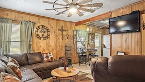 A cozy living room with a leather sofa, a wooden coffee table, and a television mounted on the wall.
