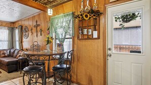 A cozy room with a wooden interior, a dining table with four chairs, a sofa, and a door with a window.